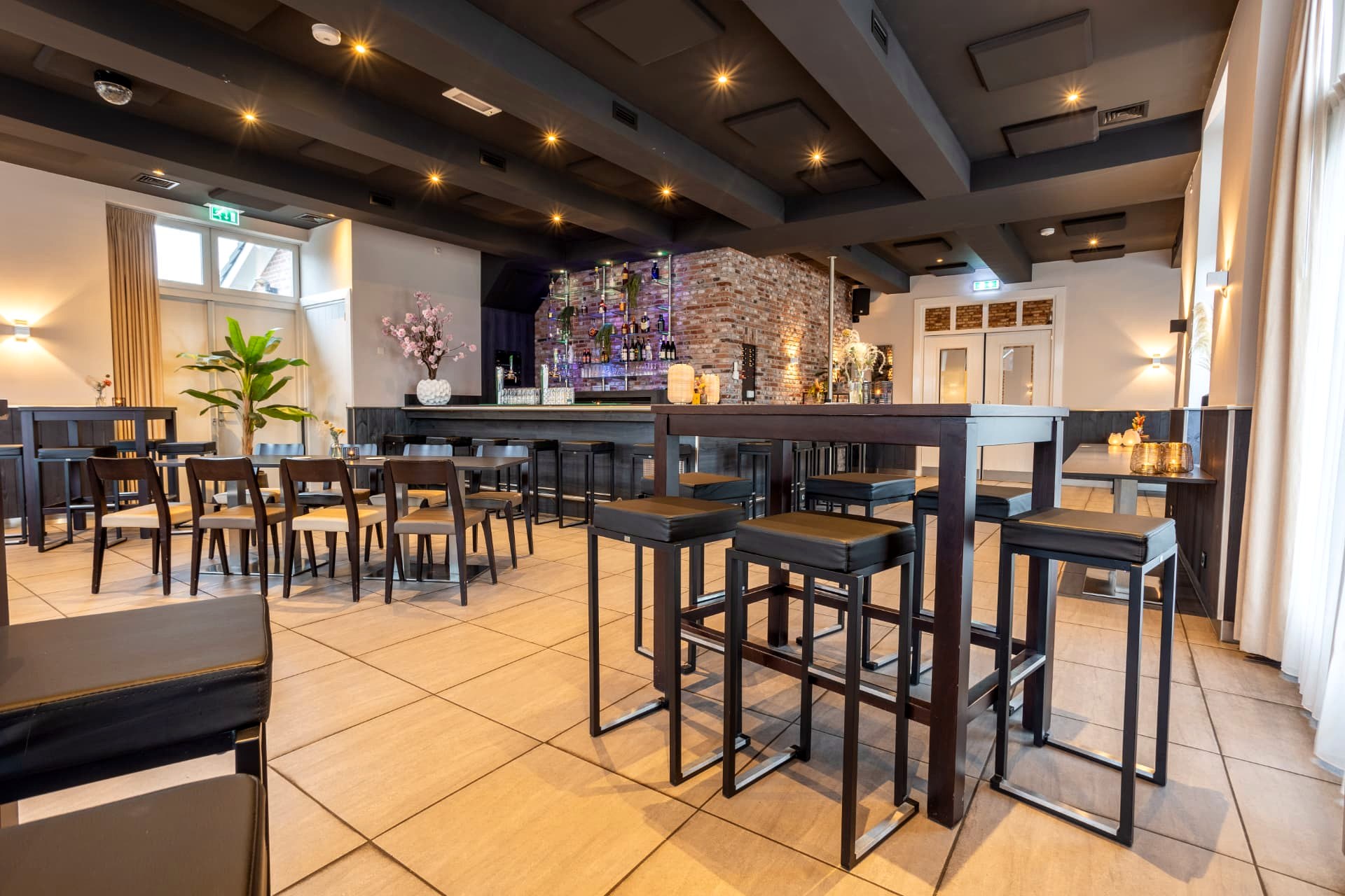 Borrelruimte met bar, barkrukken en bakstenen achterwand bij D' Olde Skoele Rouveen