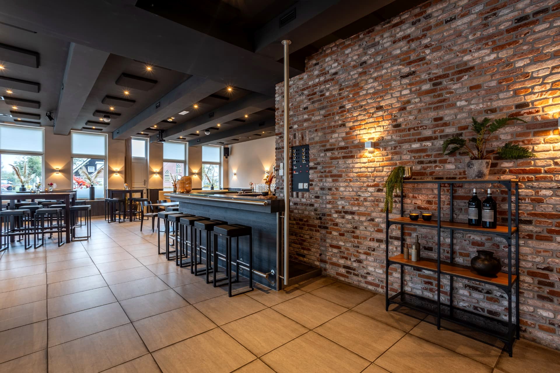Bakstenen muur en bar met barkrukken in de borrelzaal van D' Olde Skoele Rouveen