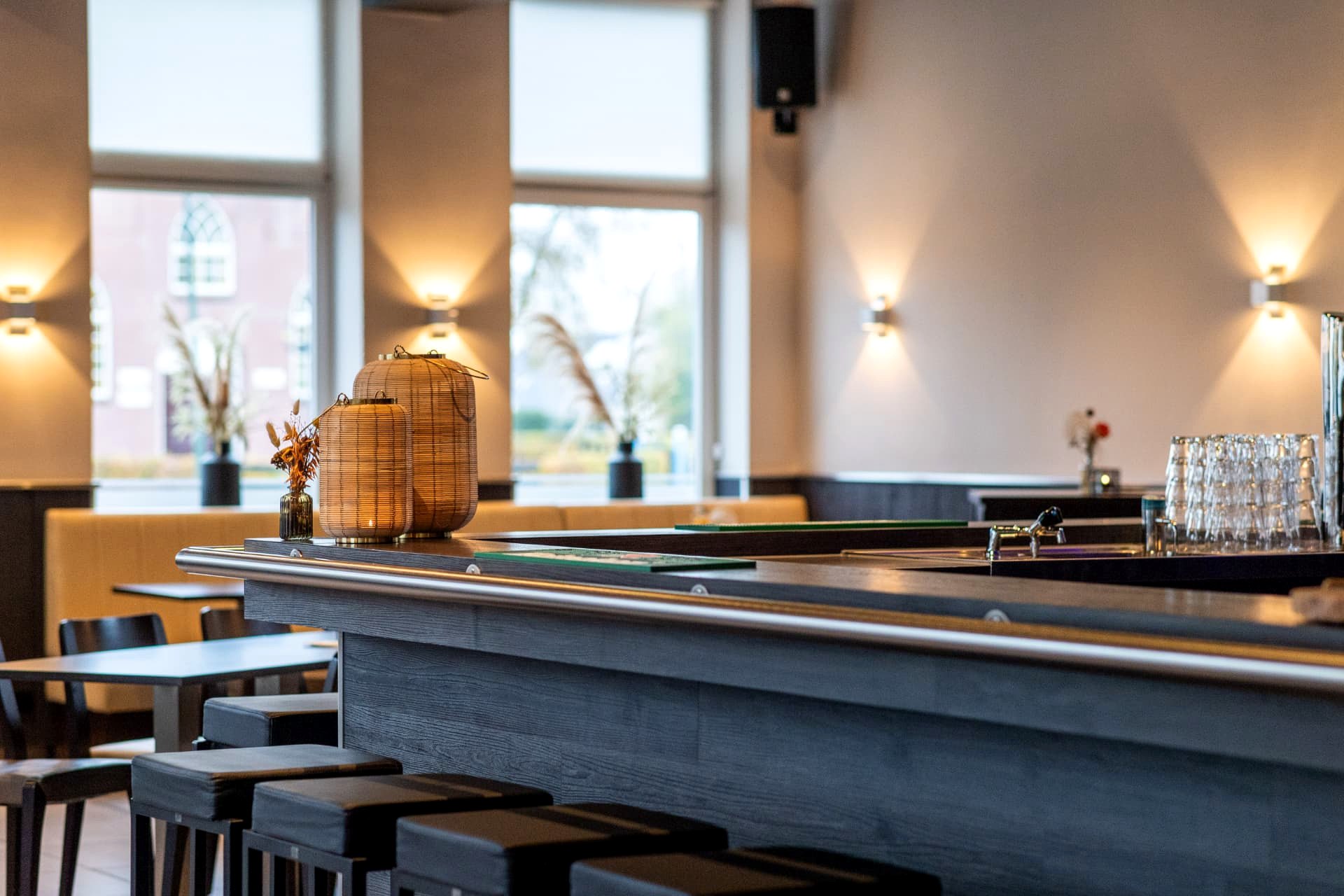 Bar met uitzicht op de zaal en hoge ramen bij D' Olde Skoele in Rouveen
